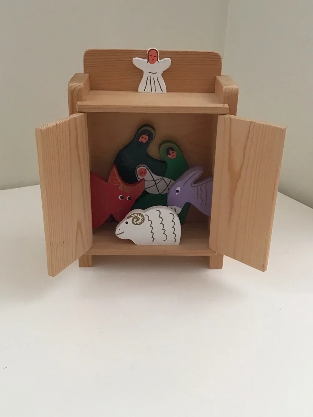 Handmade wooden cabinet holding a small wooden Nativity set